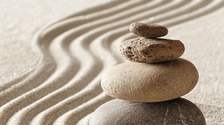 Stacked stones in the sand, symbolizing community and shared reflection
