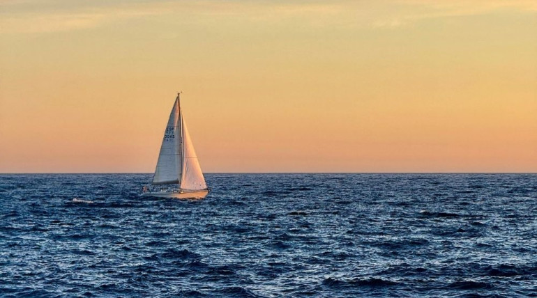 Small sailboat on calm water at sunset, symbolizing adventure and humor in aging