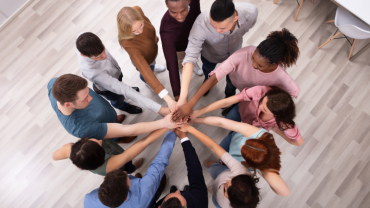 Circle of people with hands joined in the center, symbolizing democracy and community care