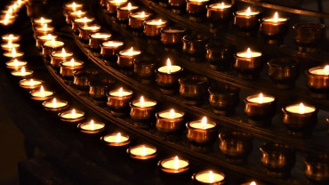 A circle of softly glowing candles in dim light, symbolizing the warmth and meaning of ritual held with gentleness and without attachment.