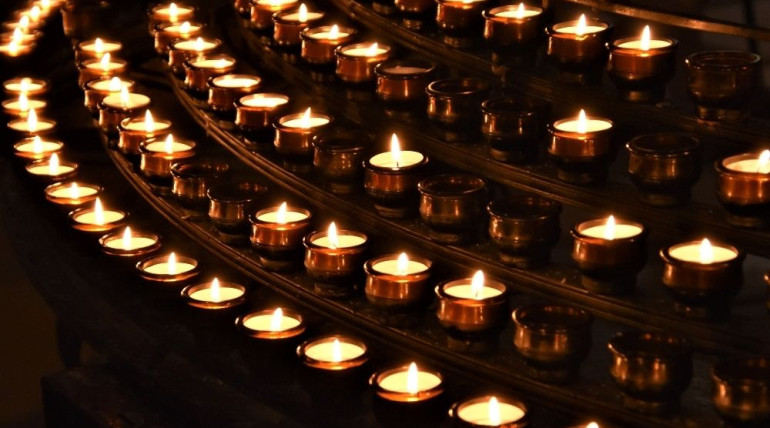 A circle of softly glowing candles in dim light, symbolizing the warmth and meaning of ritual held with gentleness and without attachment.