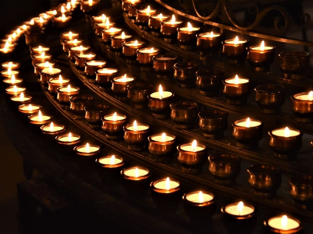A circle of softly glowing candles in dim light, symbolizing the warmth and meaning of ritual held with gentleness and without attachment.